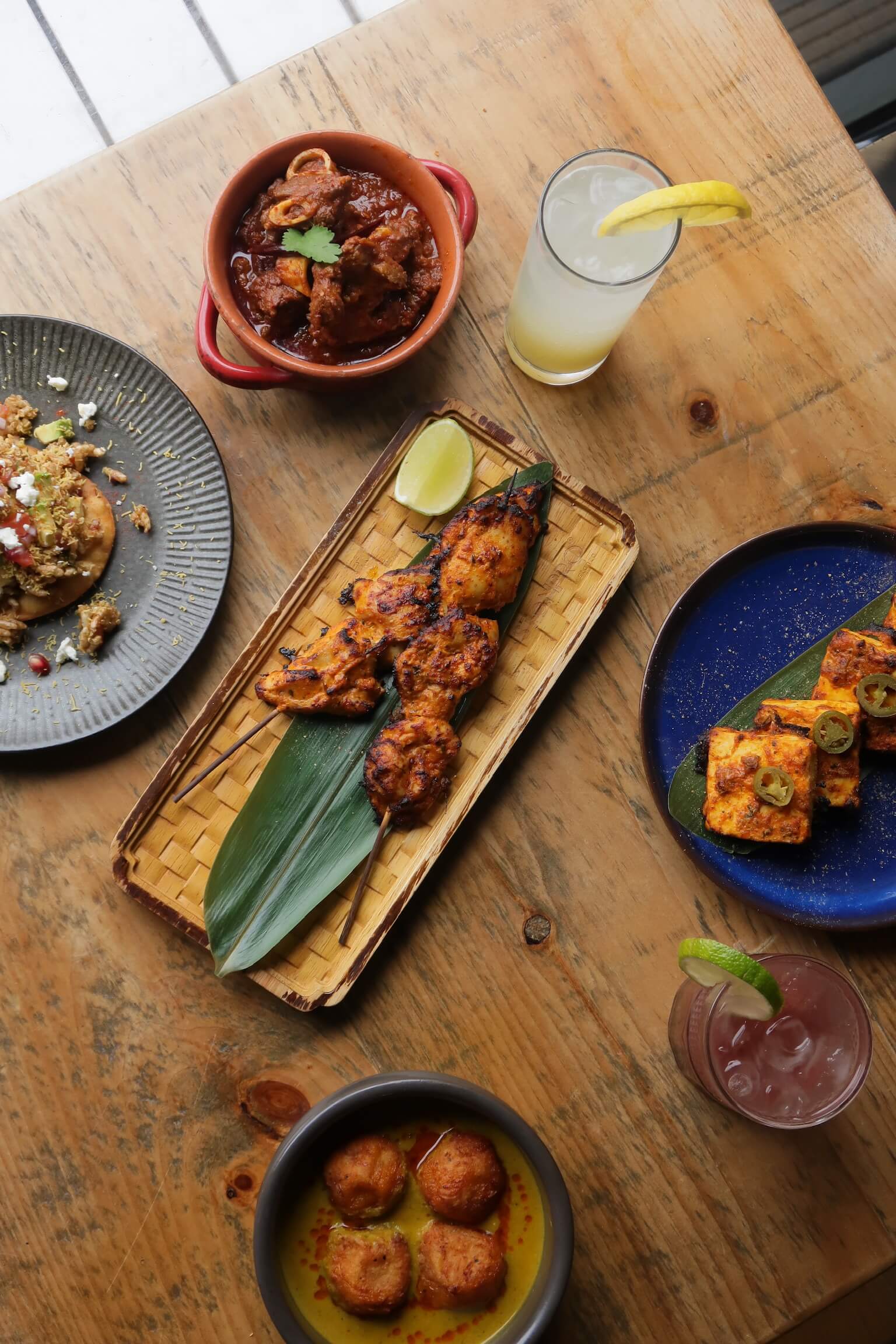 Assorted Indian dishes and drinks served on a wooden table.