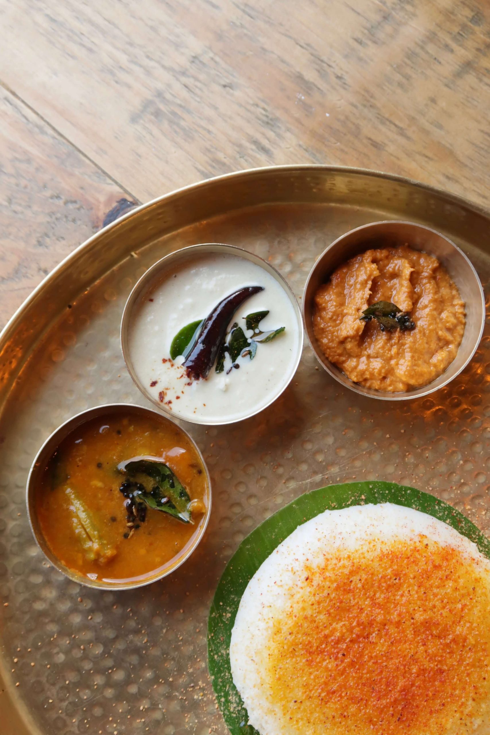 South Indian meal of idli, sambar, and chutneys served on a traditional platter.